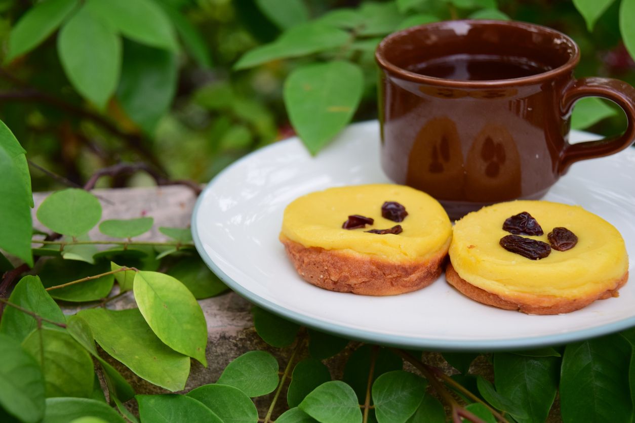 Kue Lumpur, Indonesian cuisine, made from potato, egg, coconut milk, butter, flour and sugar garnish with raisin. Served with cup of tea. Snack for breaking the fast or buka puasa