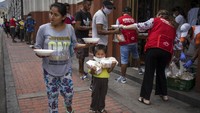 Maria Isabel Nieto dan putranya Jesus Anderson membawa makan siang mereka yang diberikan kepada para tunawisma oleh sebuah organisasi amal di Lima, Peru, Kamis (26/3/2020). Memasuki pekan kedua pemerintah menetapkan keadaan darurat dan mengkarantina diri masing-masing guna menghentikan rantai penyebaran virus Corona. AP Photo/Rodrigo Abd.
