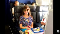 Wanita yang hobi menembak ini sedang pose di pesawat. Ia disuguhi makanan, lengkap dengan jus apel dingin. Foto: Instagram roro.fitria1989