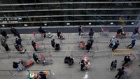 Penjual dan pembeli juga berusaha mengurangi kontak fisik. Salah satu caranya dengan mengenakan masker dan sarung tangan. Selain itu mereka juga tak pernah lepas dari cairan desinfektan yang bisa membunuh kuman, bakteri dan virus. Foto: AFP via Getty Images/ANNE-CHRISTINE POUJOULAT