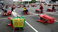 Saking banyaknya orang yang menyerbu supermarket membuat pembeli harus rela antre menunggu giliran. Ketika antre pun tetap menerapkan sistem jaga jarak. Area parkir mobil disulapnya jadi area antre. Foto: AFP via Getty Images/ANNE-CHRISTINE POUJOULAT