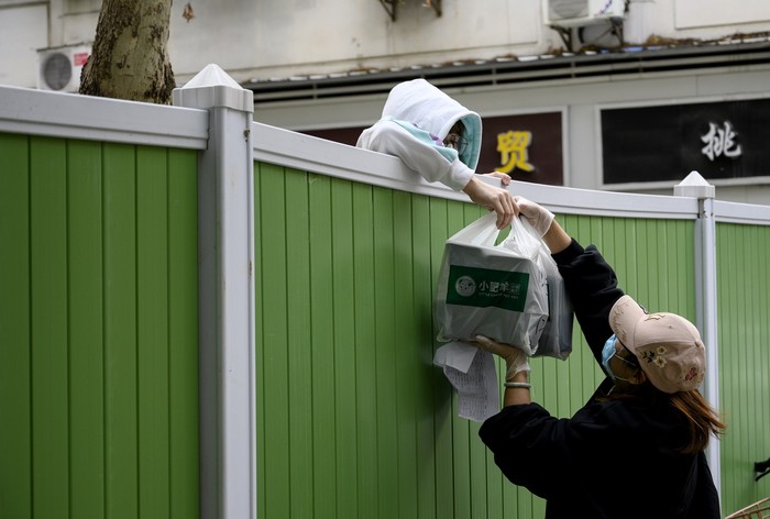 TOPSHOT - An inhabitant of the residence Maison Blanche (White House residence), composed of 226 mostly unsanitary dwellings, collects food offered by neighbours from his balcony, using a rope made with blankets, on March 31, 2020, in Marseille, southern France, on the fifteenth day of a lockdown aimed at curbing the spread of the COVID-19 (novel coronavirus). (Photo by Anne-Christine POUJOULAT / AFP) (Photo by ANNE-CHRISTINE POUJOULAT/AFP via Getty Images)