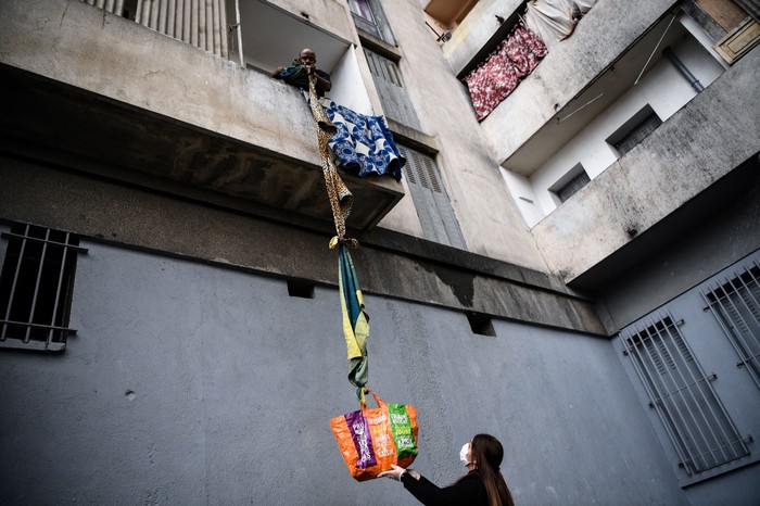 TOPSHOT - An inhabitant of the residence Maison Blanche (White House residence), composed of 226 mostly unsanitary dwellings, collects food offered by neighbours from his balcony, using a rope made with blankets, on March 31, 2020, in Marseille, southern France, on the fifteenth day of a lockdown aimed at curbing the spread of the COVID-19 (novel coronavirus). (Photo by Anne-Christine POUJOULAT / AFP) (Photo by ANNE-CHRISTINE POUJOULAT/AFP via Getty Images)