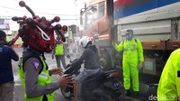 Sesekali, saat traffic light menyala merah, mereka mendekati pengendara. Sejumlah anggota lainnya menyemprotkan cairan disinfektan ke kendaraan dan tubuh pengendara.
