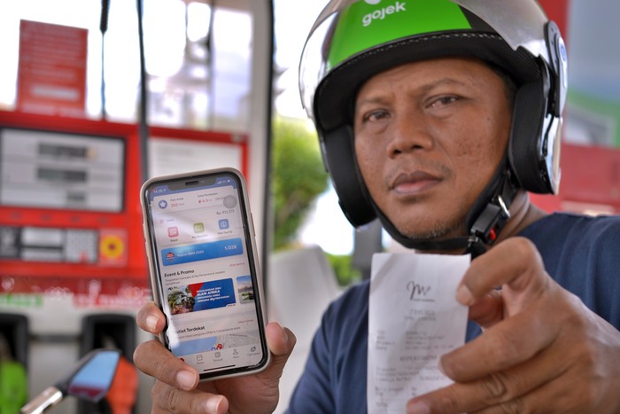 Salah satu ojek daring memperlihatkan aplikasi My Pertamina untuk transaksi pengisian bahan bakar di salah satu Stasiun Pengisian bahan bakar Umum (SPBU) di Manado, Sulawesi Utara, Jumat (3/4/2020). Program Pejuang Tangguh Pertamina ditujukan untuk mempermudah pengemudi ojek daring yang harus tetap berada di luar rumah untuk mencari nafkah di saat pandemi COVID-19, dengan menggunakan aplikasi My Pertamina sehingga mengurangi kontak fisik, serta mendapatkan potongan harga untuk pembelian produk Pertamax dan penggantian oli gratis juga mendapatkan multivitamin. ANTARA FOTO/Adwit B Pramono/aww.
