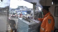 Petugas penjaga perlintasan kereta api tetap harus bekerja demi keselamatan pengguna jalan lainnya di tengah wabah virus Corona yang semakin merajalela.
