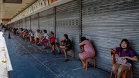 Para pembeli duduk di kursi yang sudah diberi jarak ketika mereka mengantri di luar sebuah swalayan toko pangan di Manila, Filipina, Jumat (3/4/2020).