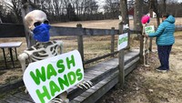 Seorang warga menggunakan kerangka dekoratif untuk menyimpan pesan yang mengingatkan publik tentang tindakan pencegahan coronavirus yang tepat, di Freeport, Maine. AP Photo/Robert F. Bukaty.
