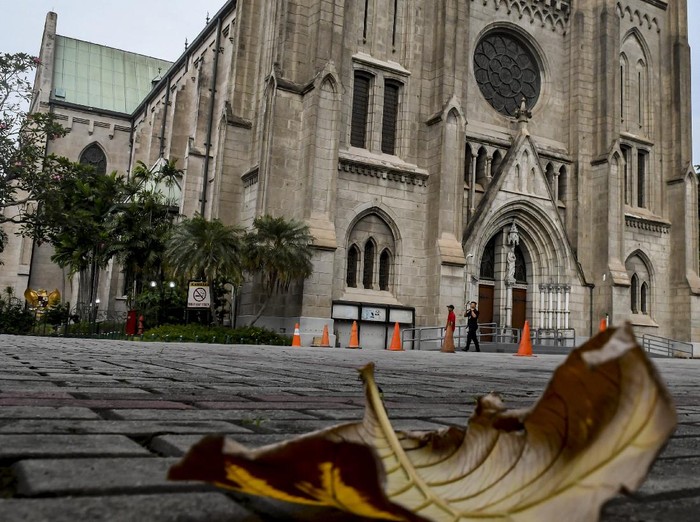 Petugas kebersihan melintas di depan pintu Gereja Katedral, Jakarta, Minggu (5/4/2020). Pasca Kemenkes resmi merilis Peraturan Menteri Kesehatan No.9 Tahun 2020 tentang Pembatasan Sosial Berskala besar (PSBB) dalam Rangka Percepatan Penanganan COVID-19, bentuk ibadah misa gereja dilakukan secara live streaming melalui media sosial, termasuk rangkaian ibadah paskah yang akan jatuh mulai Kamis (16/4/2020) hingga Minggu (19/4/2020). ANTARA FOTO/Muhammad Adimaja/foc.