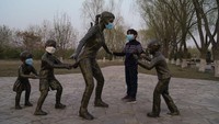 Tampak seorang anak bermain dengan patung yang menggunakan masker saat masa pemullihan pasca Covid-19 di Beijing China. Saat  masa pemulihan, banyak warga China mulai memberanikan diri untuk beraktivitas di luar ruangan, setidaknya mulai membiasakan diri sebagai layaknya hidup sebagai manusia. Getty Images/Lintao Zhang.