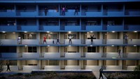 Penghuni apartemen berolahraga ringan di balkon masing-masing di Nantes, Prancis. (REUTERS/Stephane Mahe)