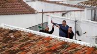 Sekeluarga menghibur dan menyemangi tetangganya dengan musik dari teras rumah mereka di Ronda, Spanyol. (REUTERS/Jon Nazca)