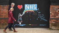 Graffiti yang menggambarkan logo Layanan Kesehatan Nasional Inggris (NHS) dan pelangi, sebagai tanda cinta dan terima kasih kepada staf NHS dan semua pihak yang terlibat dalam merawat pasien Covid-19, digambarkan di gerbang ke sebuah pub tertutup di Pontefract, Inggris (Oli Scarff/AFP)