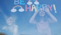 Kakak bradik ini pun menuliskan kata Be Happy dari jendela rumah mereka di St Helens, Inggris. (REUTERS/Phil Noble)