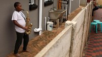 Ntsika Ntsele, remaja 13 tahun bermain saxophone untuk tetangganya sewaktu karantina di Soweto, Afrika Selatan. (REUTERS/Siphiwe Sibeko)
