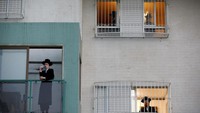 Karena tidak bisa beribadah ke luar, orang-orang Yahudi berdoa di rumah masing-masing di Ashdod, Israel. (REUTERS/Amir Cohen)