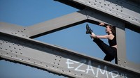 Anna melakukan peregangan otot dan pemanasan di antara balok baja di jembatan kota Kaiserslautern, Jerman (6/4/2020). 