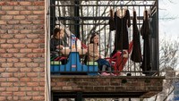 Anak-anak menikmati makanannya dari balkon rumah di New York City. (REUTERS/Jeenah Moon)