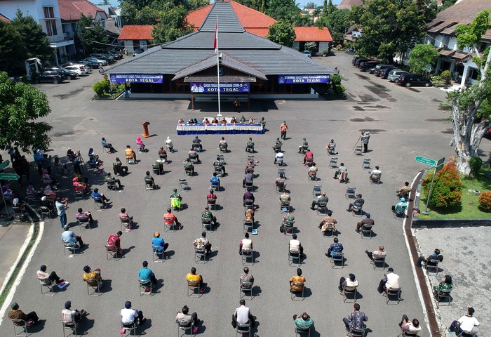 Foto aerial sejumlah Forum Koordinasi Pimpinan Daerah (Forkopimda), TNI dan Polres Tegal Kota mengikuti Rapat Percepatan Penanganan COVID-19 di halaman Kantor Pemerintah Kota Tegal, Jawa Tengah, Selasa (7/4/2020). Rapat yang diselenggarakan di luar gedung sambil berjemur tersebut sebagai bentuk menjaga kebugaran dan imunitas tubuh. ANTARA FOTO/Oky Lukmansyah/foc.