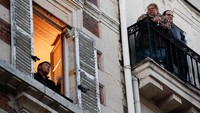 Terlihat seorang pemuda bernyanyi dari jendela apartemennya untuk menghibur tetanggganya di Paris, Perancis. (REUTERS/Gonzalo Fuentes)