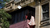 Terlihat pria paruh baya bermain biola dari balkon rumahnya sesaat pengantar paket lewat rumahnya di Rio de Janeiro, Brazil. (REUTERS/Ricardo Moraes)