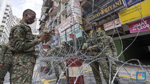 A resident collects a food delivery behind barbed wire outside a building under lockdown in downtown Kuala Lumpur, Malaysia, on Tuesday, April 7, 2020. The Malaysian government issued a restricted movement order to the public to help curb the spread of the new coronavirus. The new coronavirus causes mild or moderate symptoms for most people, but for some, especially older adults and people with existing health problems, it can cause more severe illness or death. (AP Photo/Vincent Thian)