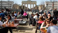 Orang-orang menikmati cuaca cderah di Brandenburg Gate di Berlin, Jerman. Foto ini diabadikan pada tanggal 4 April 2018. (REUTERS/Fabrizio Bensch)