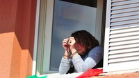 Seorang wanita berdoa dari jendela rumahnya di Grosseto, Italia. (REUTERS/Jennifer Lorenzini)