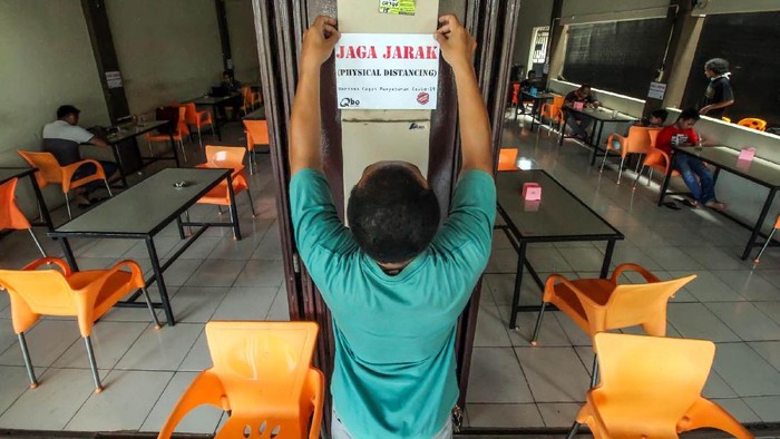 PHYSICAL DISTANCING DI RESTORAN Pelanggan duduk berjarak saat menunggu makanan pesanannya di sebuah restoran cepat saji di Surabaya, Jawa Timur, Senin (6/4/3/2020). Sejumlah restoran di Surabaya memilih tetap buka namun hanya melayani pesanan untuk dibawa pulang guna mencegah penyebaran Virus Corona (COVID-19). ANTARA FOTO/Zabur Karuru/wsj.