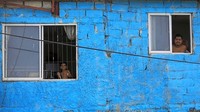 Pria dewasa dan seorang anak berdiri di jendela melihat keadaan di luar. Foto ini diambil di Colombo, Sri Lanka.