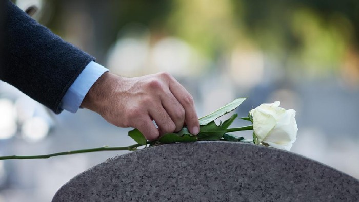 berkabung Cropped shot of a man placing a white rose on a grave