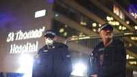 Petugas kepolisian berjaga di luar Rumah Sakit St Thomas, di London Senin (6/4/2020) malam.  Kantor PM Inggris atau Downing Street mengumumkan bahwa PM Johnson dipindahkan ke ICU sejak Senin (6/4) waktu setempat. Victoria Jones/PA via AP.