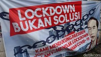 Selain bertuliskan Lockdown Bukan Solusi spanduk itu juga tampak dihiasi dengan wajah Presiden Joko Widodo (Jokowi).  