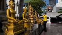 Seorang warga membersihkan patung Buddah di Thailand. Saat masa Covid-19 kebersihan tempat ibadah harus selalu diutamakan. Getty Images/Lauren DeCicca.  