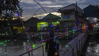 Meski belum menerima ijin dari Menkes soal PSBB, Pemkot Bekasi telah lebih dulu mengeluarkan kebijakan jam malam. Warga melintasi jembatan di kampung pintu air, Bekasi, Jawa Barat, Selasa (7/4/2020). Pemerintah kota Bekasi memperketat kebijakan pembatasan sosial dengan menghalau warga yang masih berkumpul diatas pukul 21.00 WIB untuk mencegah penyebaran COVID-19. Foto: ANTARA FOTO/Fakhri Hermansyah