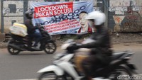Sejumlah pengendara motor melintas di samping spanduk bertuliskan Lockdown Bukan Solusi di kawasan Bandung, Jawa Barat, Rabu (8/4/2020).