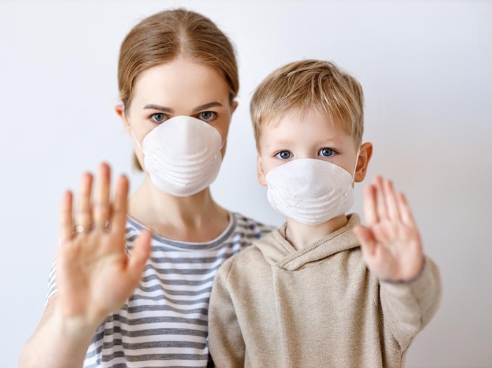 Masker Keluarga Adult woman and little boy in medical masks showing stop gesture and looking at camera during coronavirus epidemic against gray background