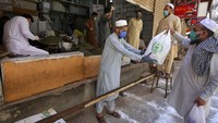 Aksi saling berbagi pun kerap dilakukan oleh umat Muslim dengan tujuan meringkan beban saudaranya saat kekurangan stok makanan saat masa wabah COVID-19. AP Photo/Fareed Khan.
