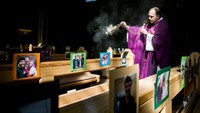 Di sebuah gereja di Austria tampak ada Pastor yang melakukan kegiatan misanya tanpa umat yang digantikan dengan fotonya saja. Saat ini para jamaah Kristen di negara itu dilarang untuk sementara waktu ke gereja dan digantikan dengan Misa online yang dapat disaksikan melalui video call. Getty Images/Jan Hetfleisch.