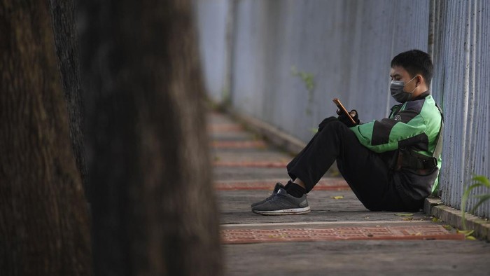 Sejak imbauan pemerintah untuk melakukan jaga jarak fisik terkait COVID-19, pendapatan para pengemudi ojek daring turun drastis. Kini penumpang kian sepi.