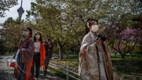 Beberapa wanita Cina, dengan kostum dinasti Qing memakai masker pelindung di Beijing, China. Getty Images/Kevin Frayer.
