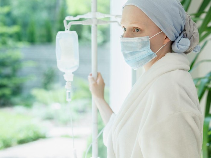 Kemoterapi Young woman with drip standing by the hospital window