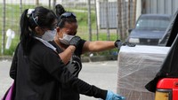 Dua orang warga menangis di sekitar peti jenazah yang terbungkus plastik di Guayaquil, Ekuador. Pandemi virus Corona membuat angka kematian di kota Guayaquil meningkat. Gara-gara pandemi virus bernama resmi Corona Virus Disease 2019 (COVID-19) itu kota Guayaquil sampai kehabisan peti mati. Getty Images/Francisco Macias.