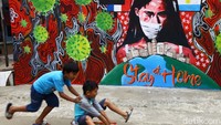 Dua orang bocah tengah beraktivitas diantara mural. 