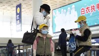 Seorang ibu dan dua orang anak memakai kaca mata dan masker menunggu penerbangan di Bandara Internasional wuhan Tianhe. (AP)