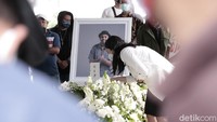 Mutia Ayu memejamkan mata dan menunduk di pusara Glennn Fredly. Foto: Hanif Hawari/detikHOT
