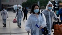 Para penumpang tiba di Stasiun Kereta Api Hankou, Wuhan. Menggunakan masker dan jas hujan, mereka ingin mengambil salah satu kereta pertama yang meninggalkan kota di provinsi Hubei. (AFP)