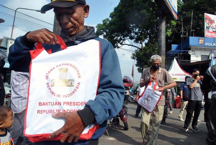 PEMBAGIAN SEMBAKO DAMPAK COVID-19 Petugas kepolisian memberikan sembako kepada juru parkir di wilayah Kota Tegal, Jawa Tengah, Kamis (9/4/2020). Pembagian paket sembako kepada pengayuh becak, juru parkir dan warga kurang mampu tersebut untuk membantu meringankan beban masyarakat kurang mampu yang terdampak COVID-19. ANTARA FOTO/Oky Lukmansyah/nz