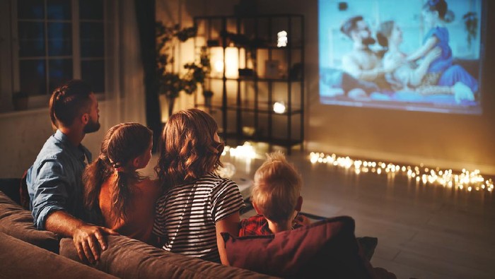 family mother father and children watching projector, TV, movies with popcorn in the evening   at home