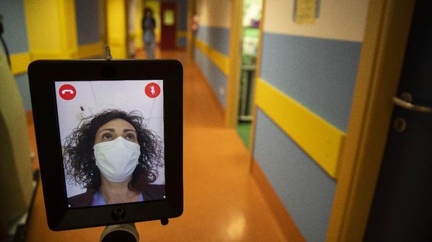 Nurse Helga drives 'Ivo' a tablet supported by a periscopic pole mounted on wheels at 'Ospedale di Circolo' in Varese, Italy, Wednesday, April 8, 2020. Ivo is remotely controlled by the healthcare professional via smartphone. It can enter the rooms and, with a video call system, put the staff in communication with the patients. The new coronavirus causes mild or moderate symptoms for most people, but for some, especially older adults and people with existing health problems, it can cause more severe illness or death. (AP Photo/Luca Bruno)